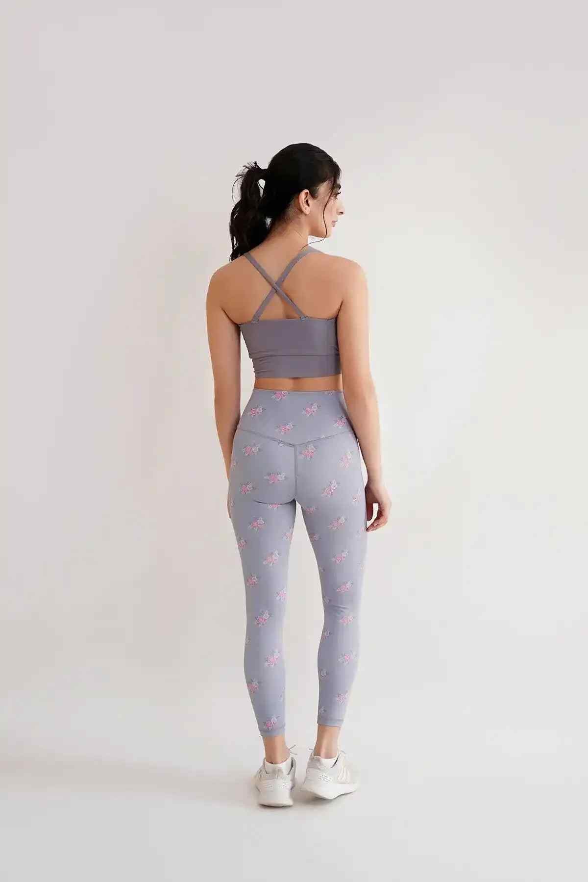 Back view: grey racerback sports bra with floral leggings, full length