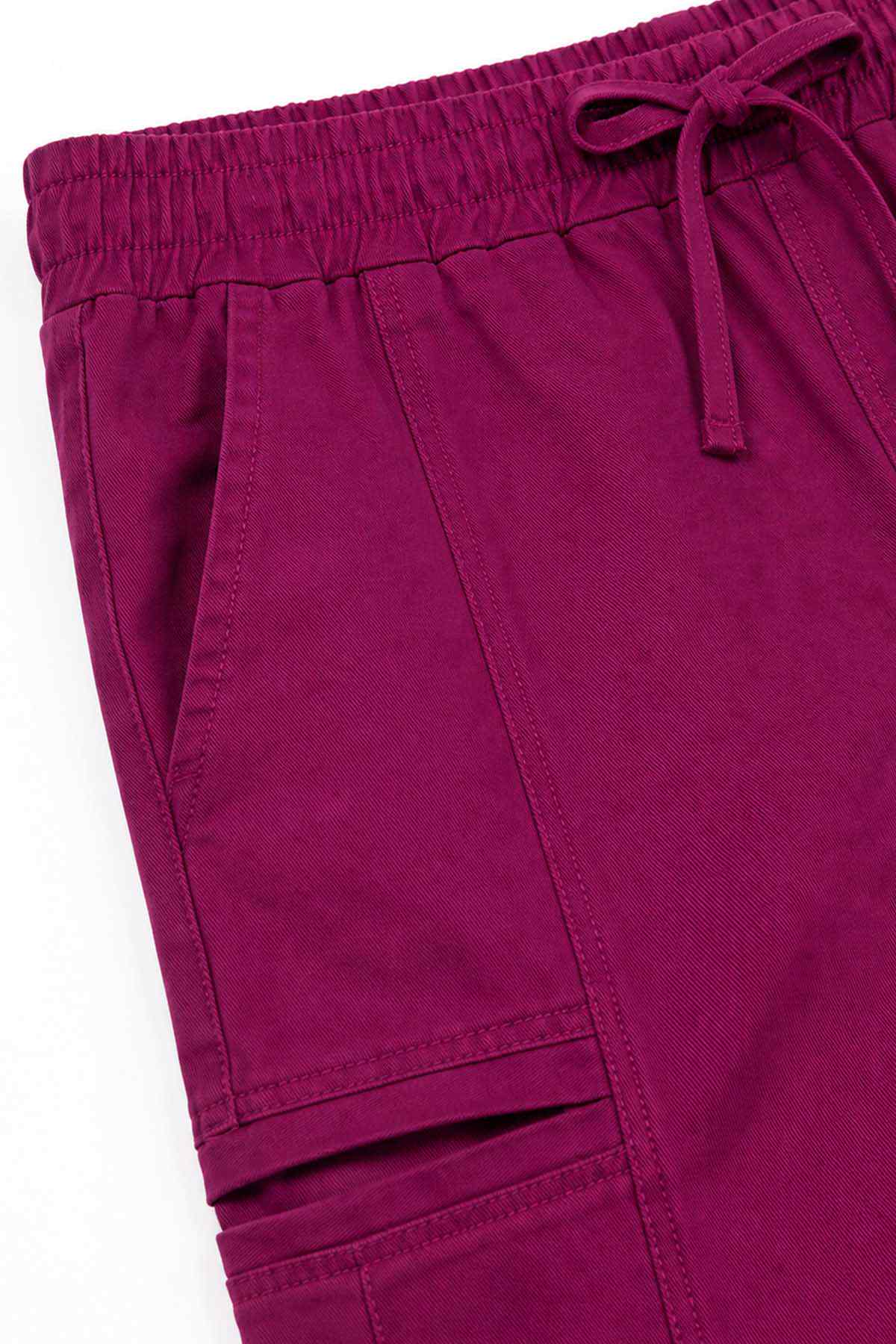 Kids' burgundy pants detail: elastic waist, drawstring and stitched pockets