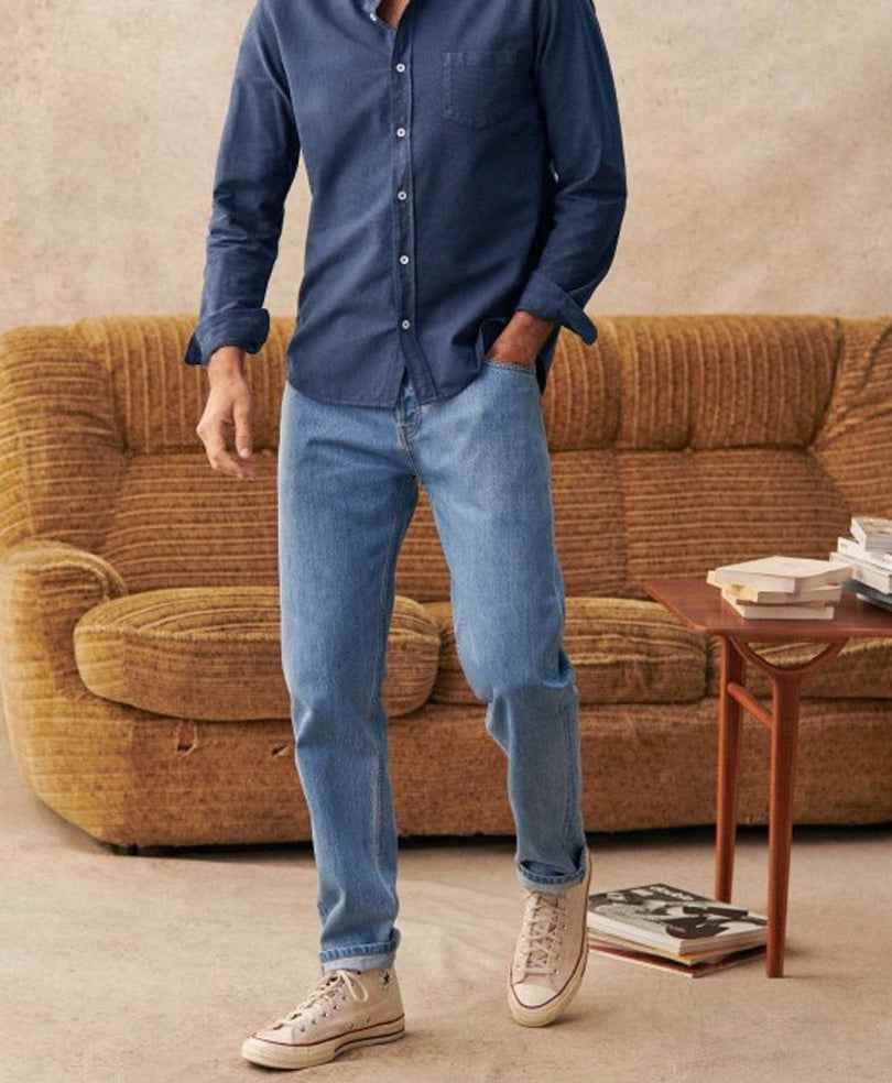 Fitted light-wash denim jeans with cuffed hems, worn with a dark shirt