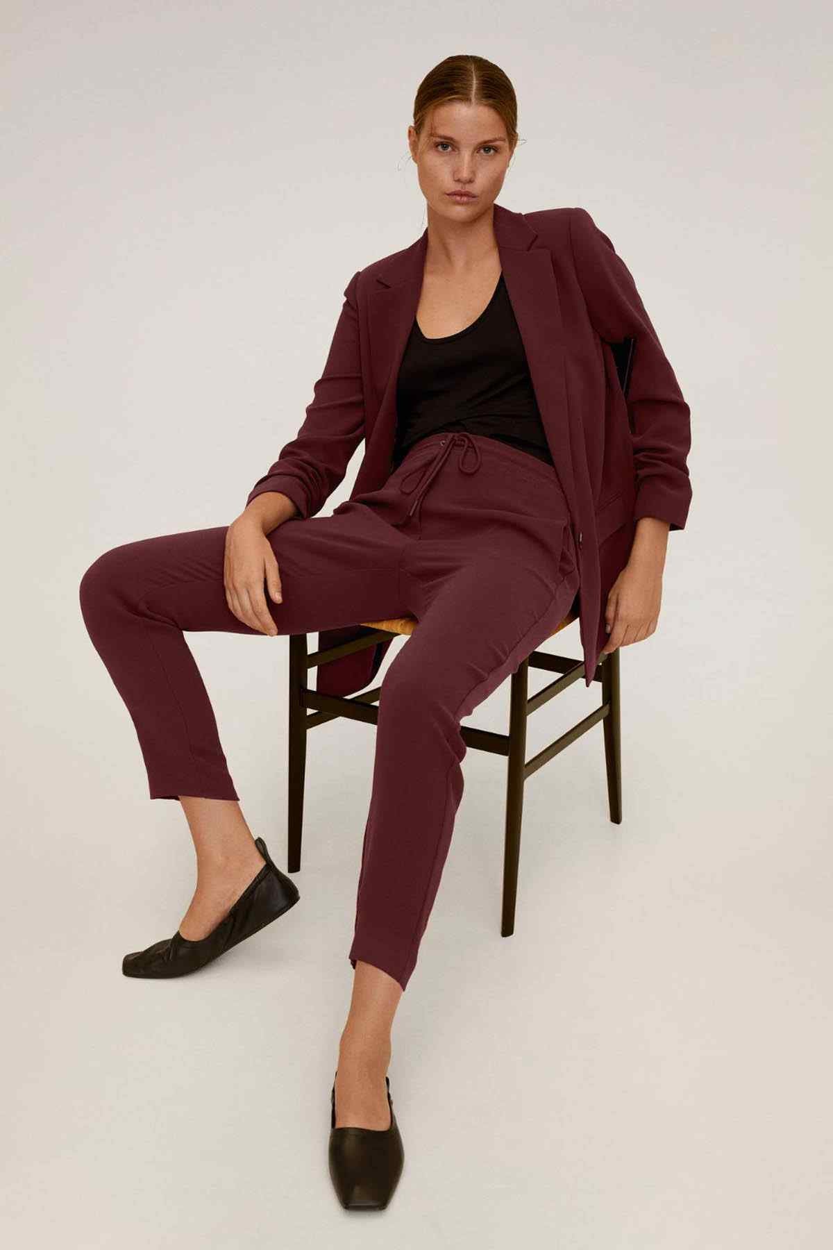 Maroon women's blazer with matching tapered trousers, seated front pose