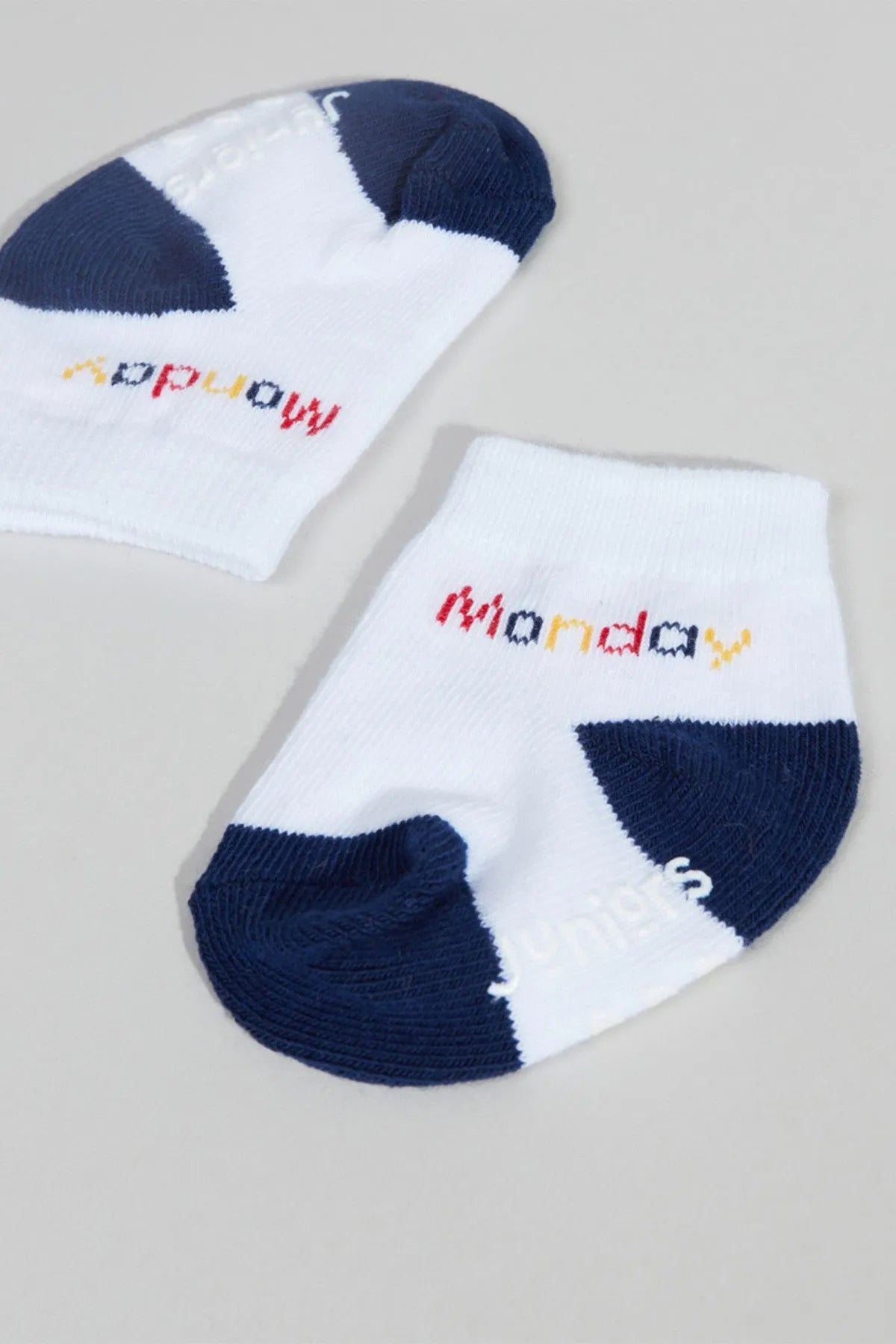 White baby ankle socks with navy heel/toe and colorful logo text, close-up pair