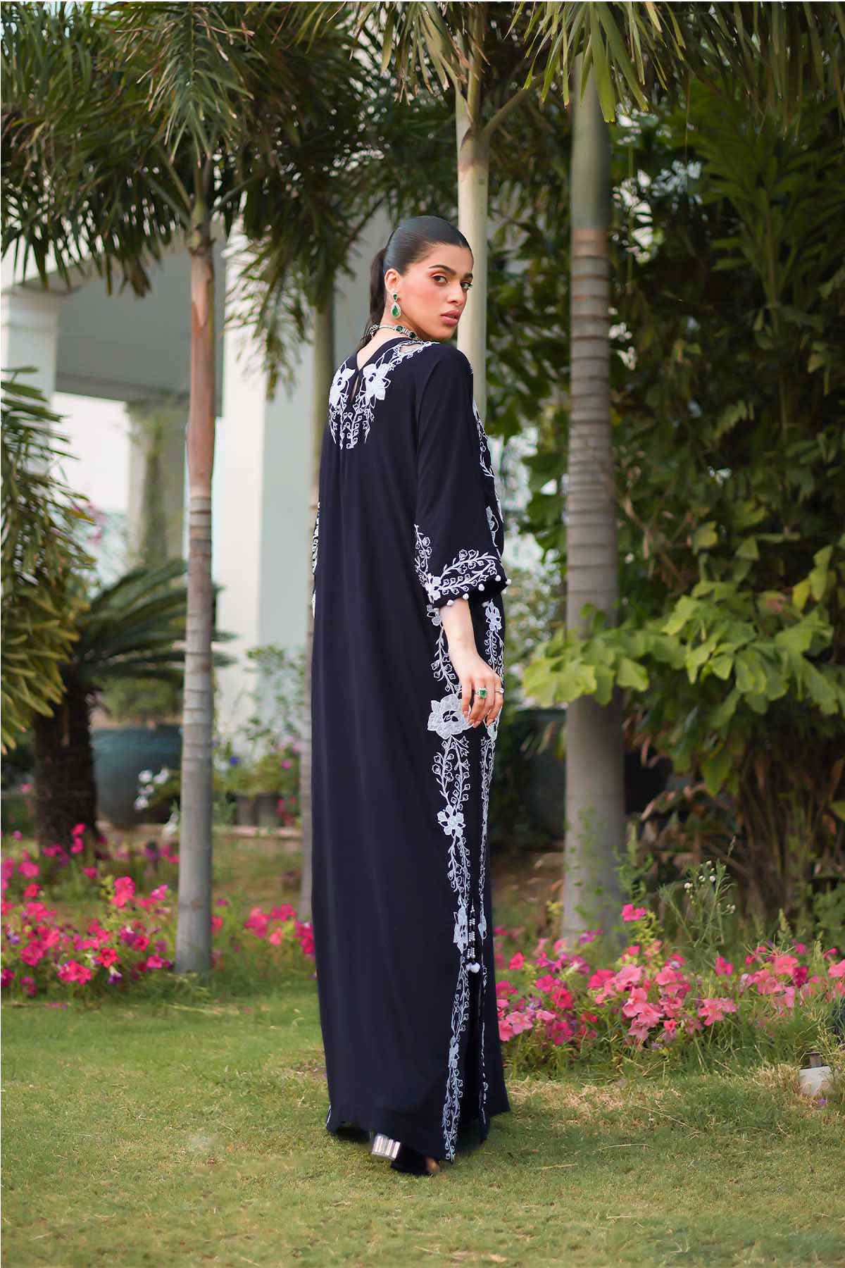 Black maxi dress side view with white floral embroidery border and long sleeves