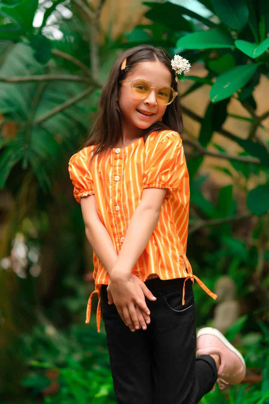 Kids orange striped shirt with tied sleeve details and black pants, front close-up