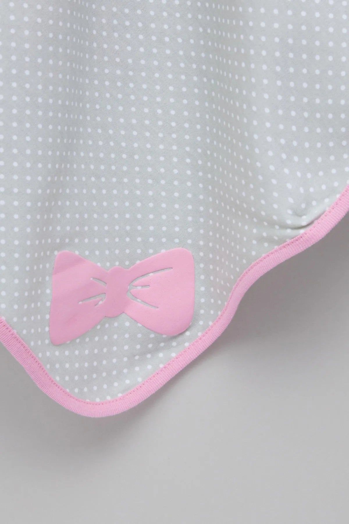 Baby blanket corner detail with pink bow applique and pink-trimmed edge