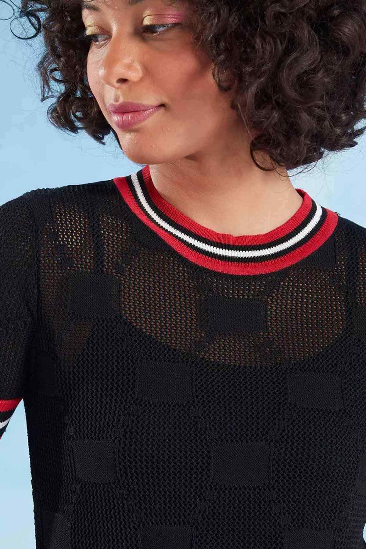 Close-up of black knit sweater with red and white striped neckline and trim