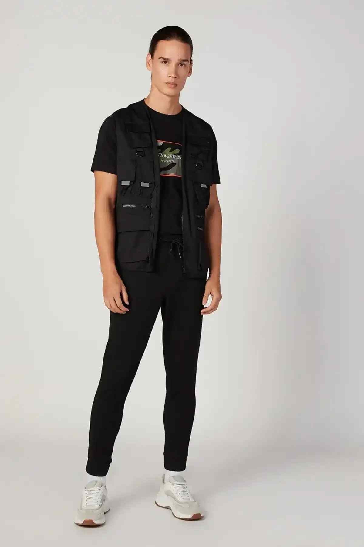 Black utility vest with front zipper, chest pockets, and side straps