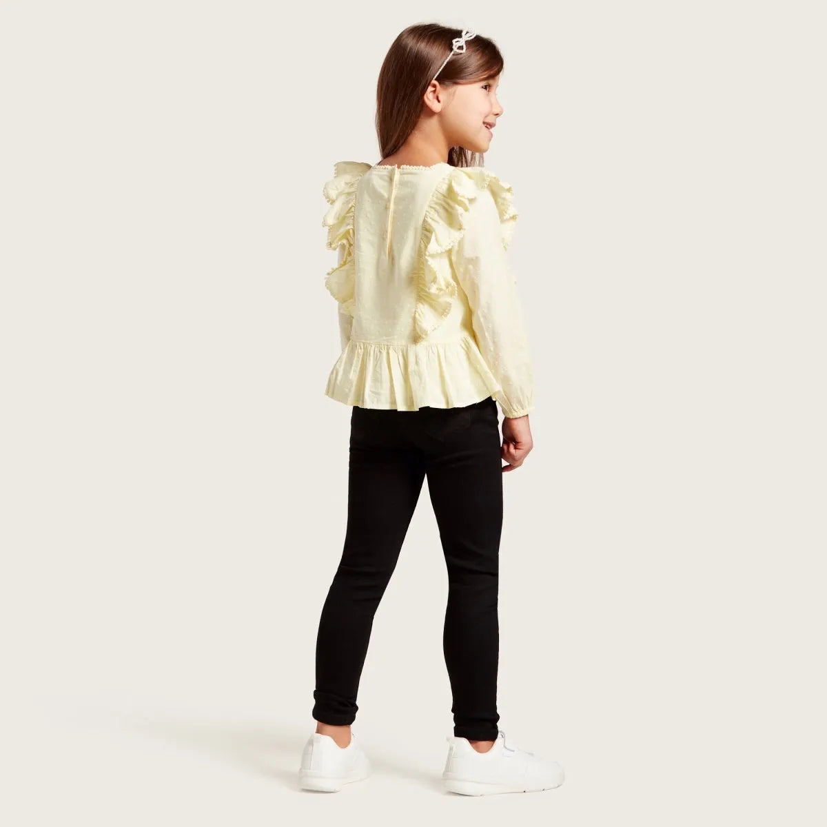 Kids ruffled yellow blouse and black leggings, side view