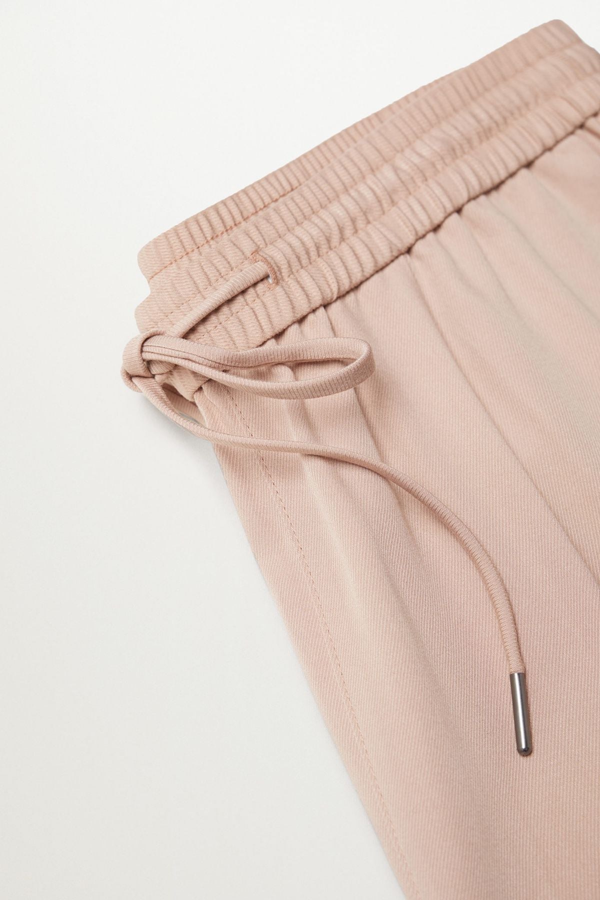 Pastel pink sweatpants waistband close-up with drawstring and elastic ruching