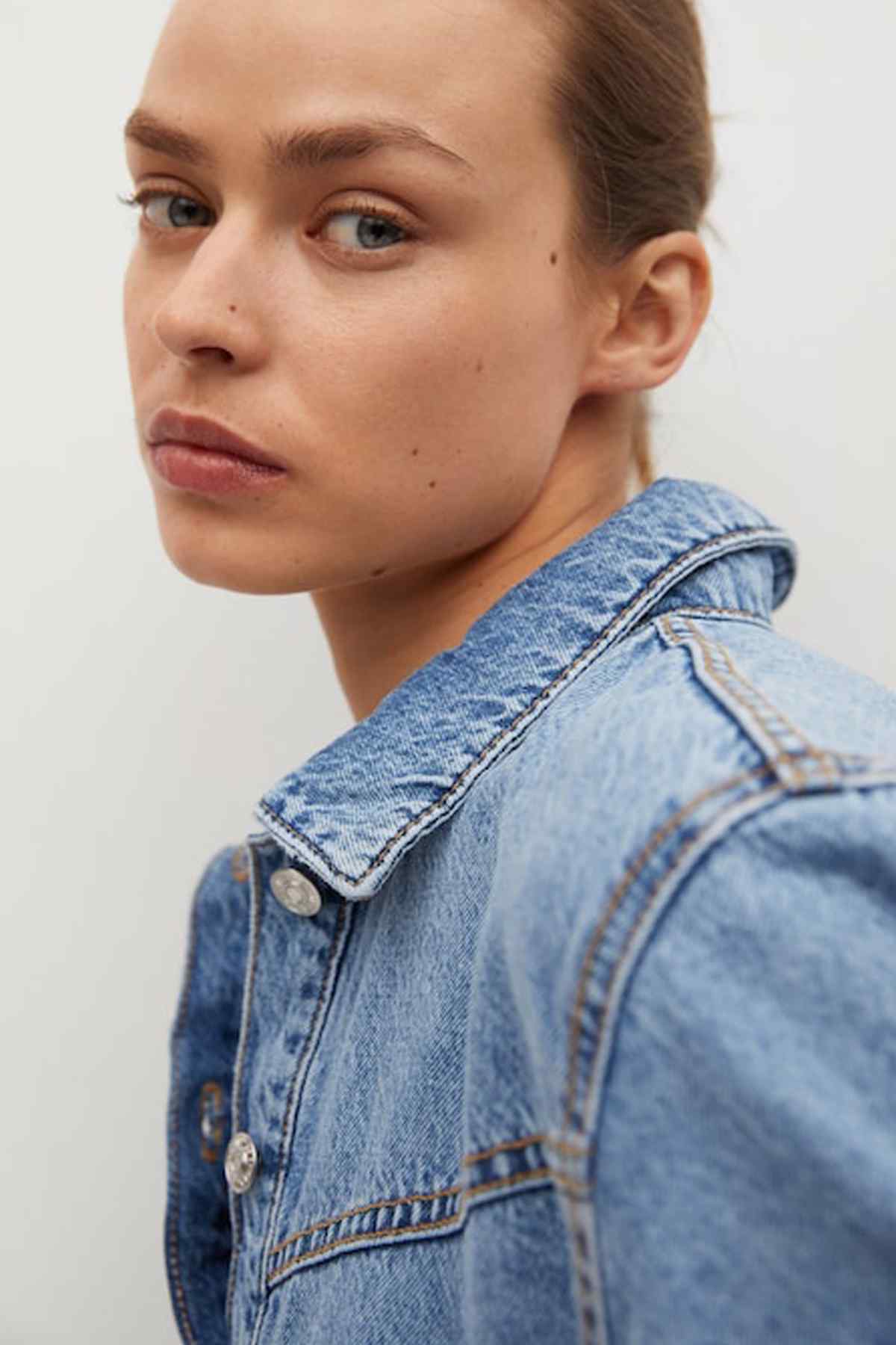 Light blue denim shirt dress close-up: pointed collar, contrast stitching, buttoned placket