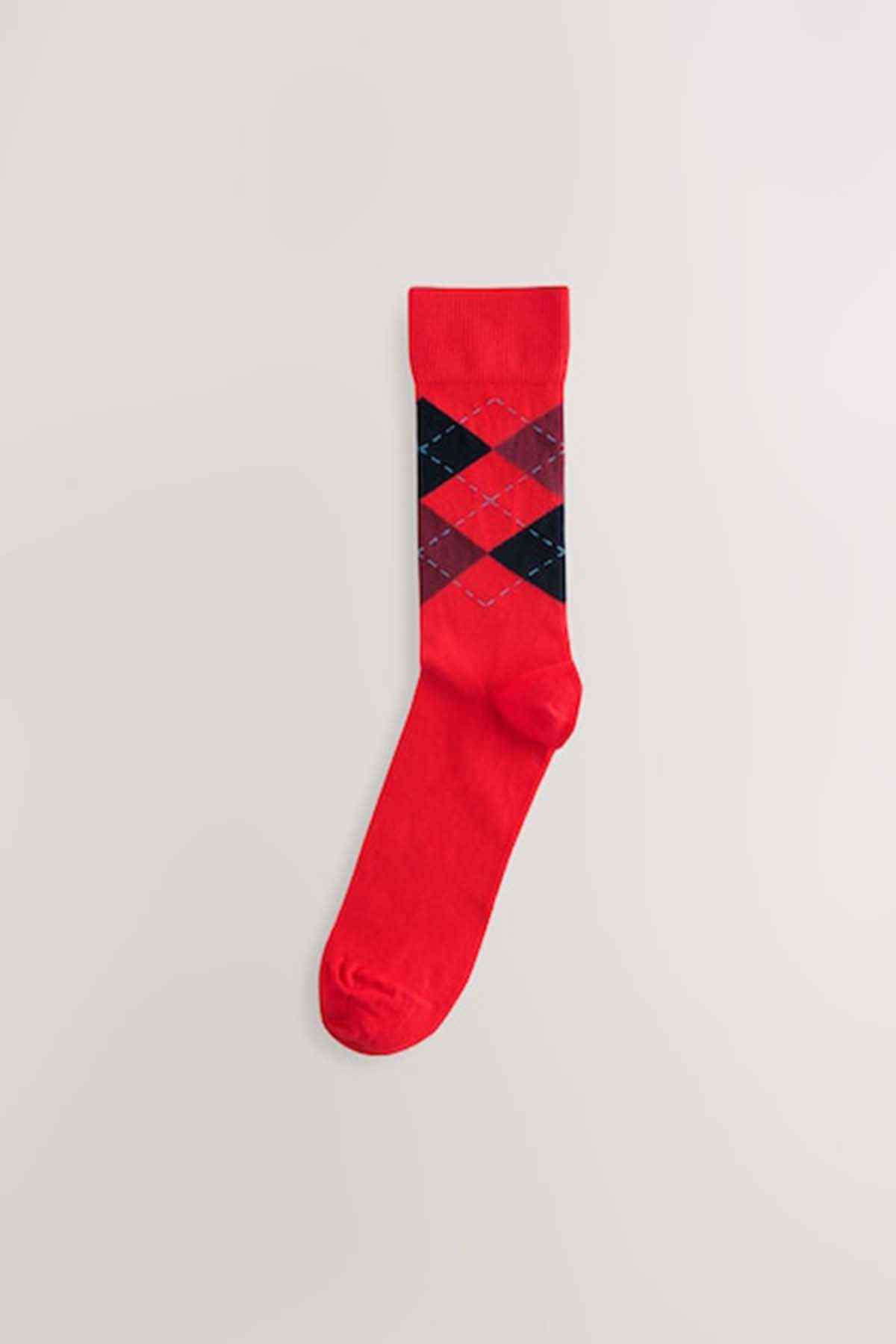 Single red argyle sock with black and blue diamond pattern; ribbed cuff
