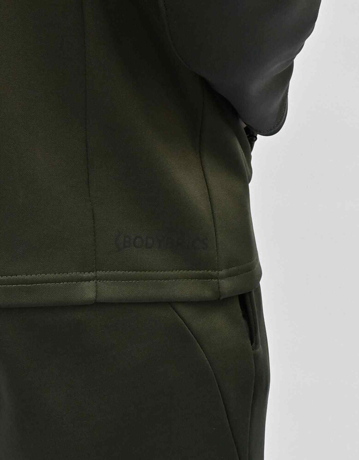 Bodybrics olive zip-up jacket with matching pants; logo text on hem area close-up
