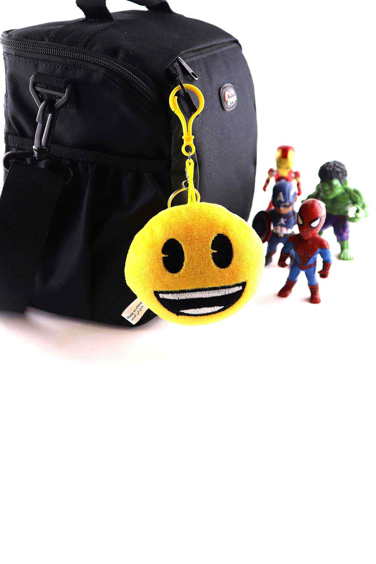 Smiley plush keychain with yellow loop attached to black backpack