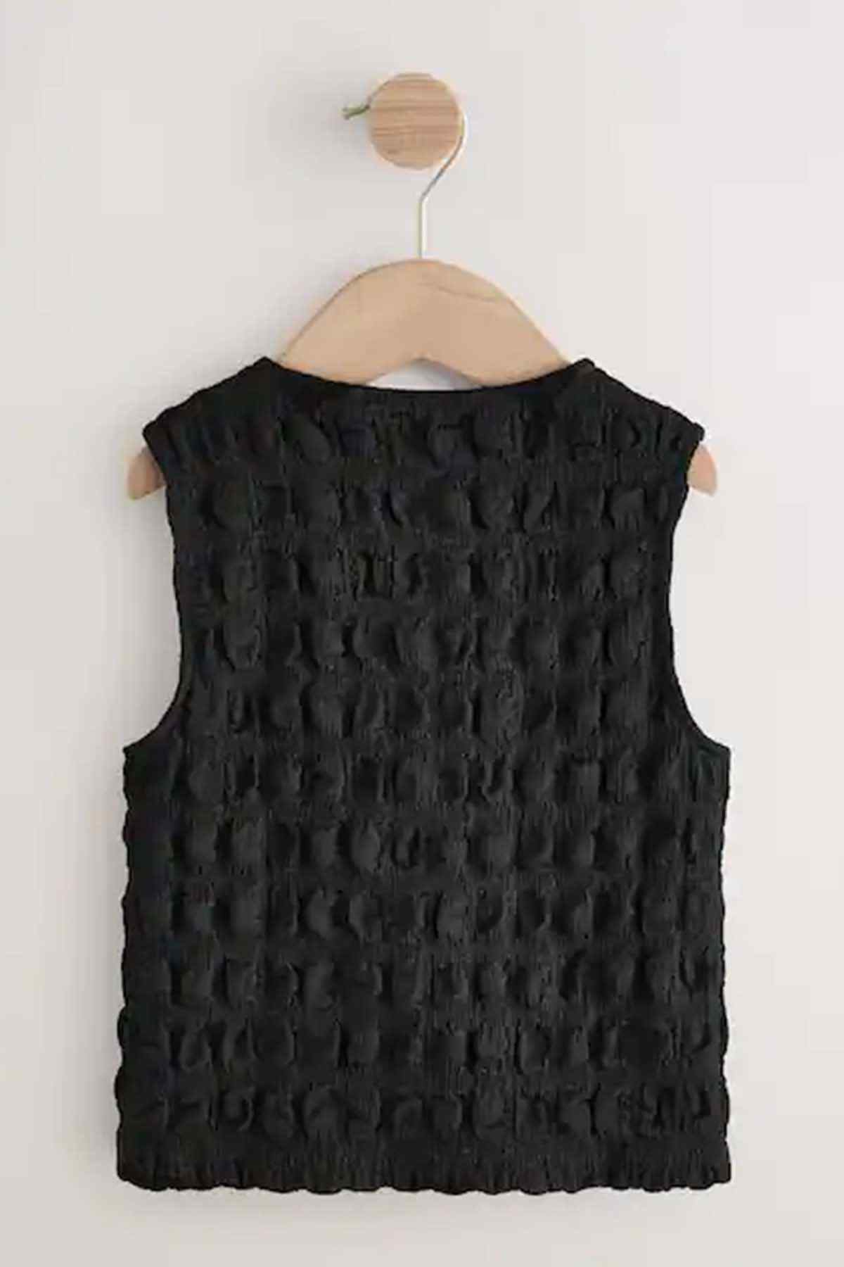 Black textured sleeveless top back view on wooden hanger