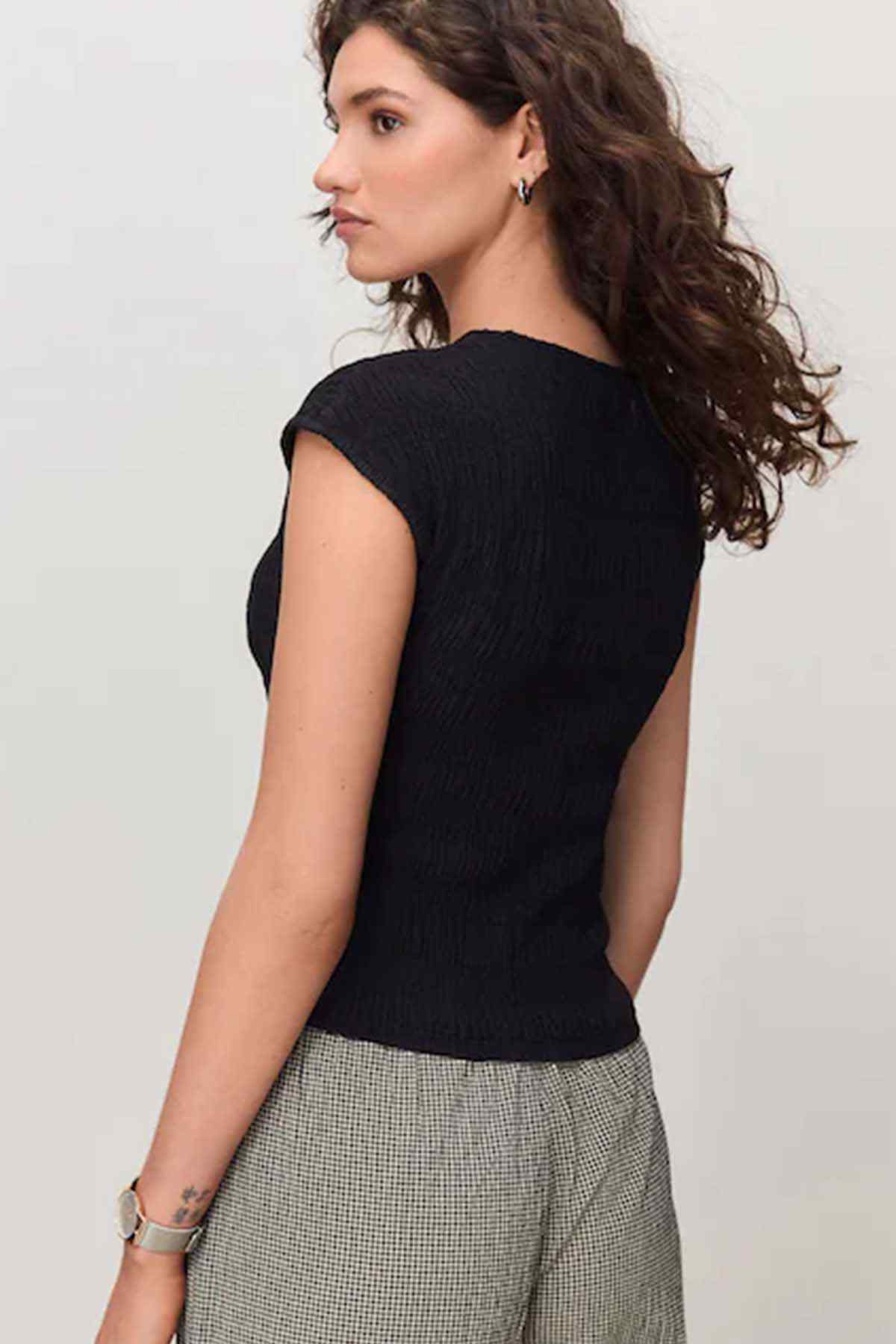 Black sleeveless knit top with crew neck and fitted waist
