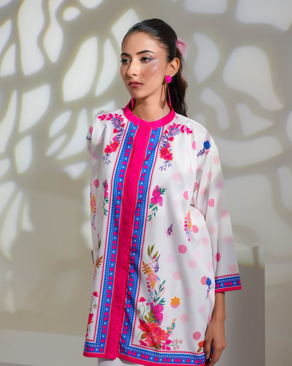 Embroidered floral tunic neckline, white fabric with pink buttons and blue trim.
