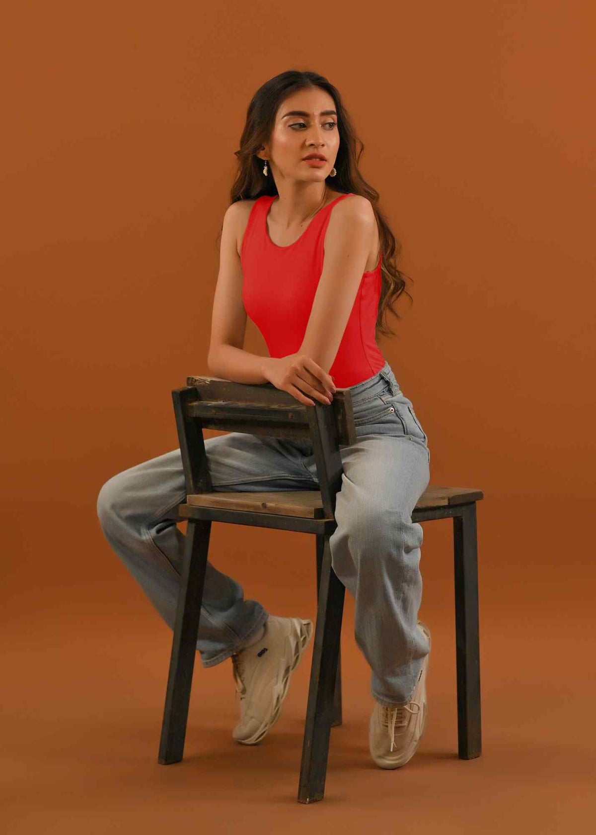 Red sleeveless tank top with light-wash straight-leg jeans, sitting view