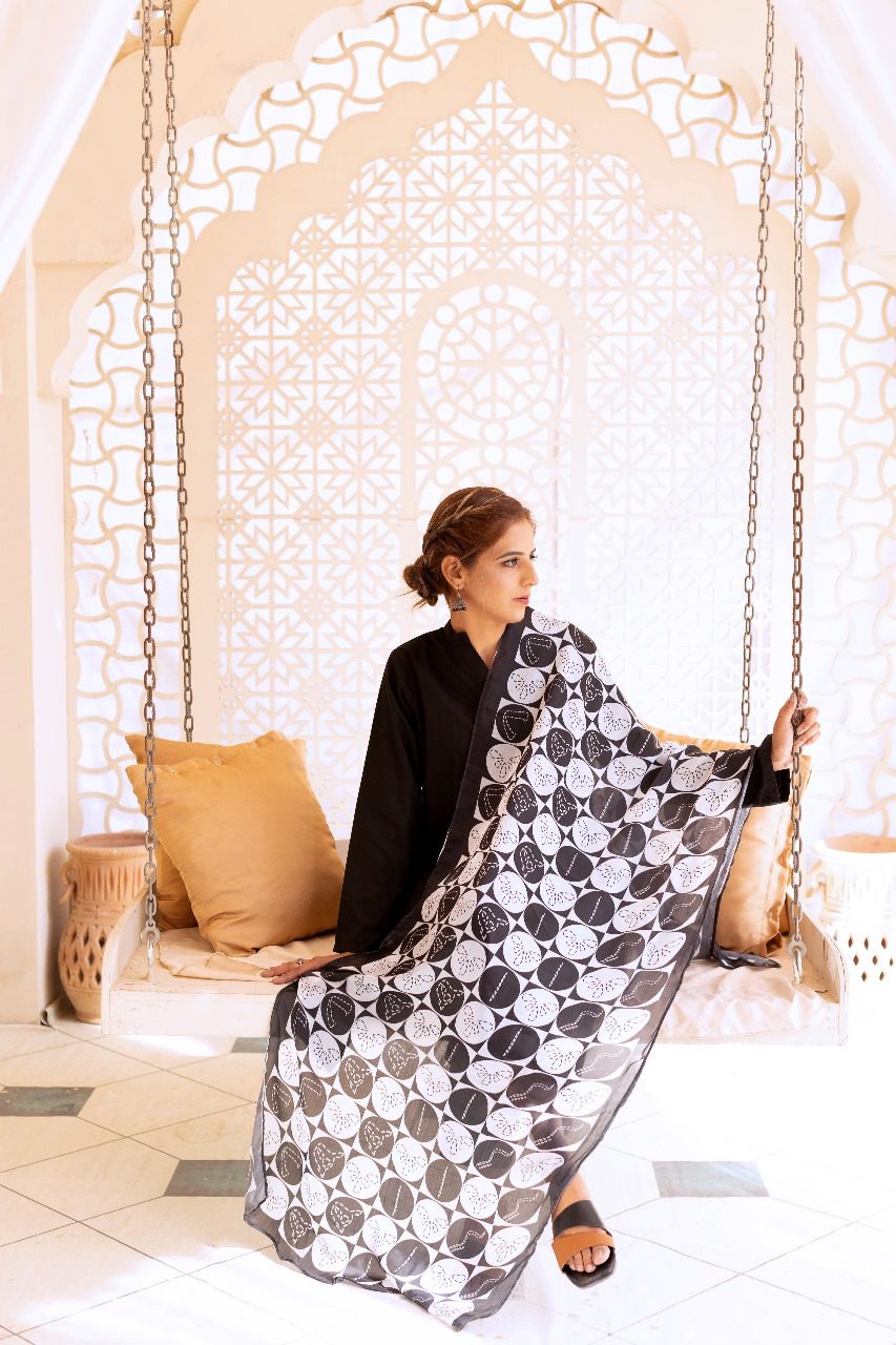 Black-and-white patterned scarf with circular motif, draped over shoulders