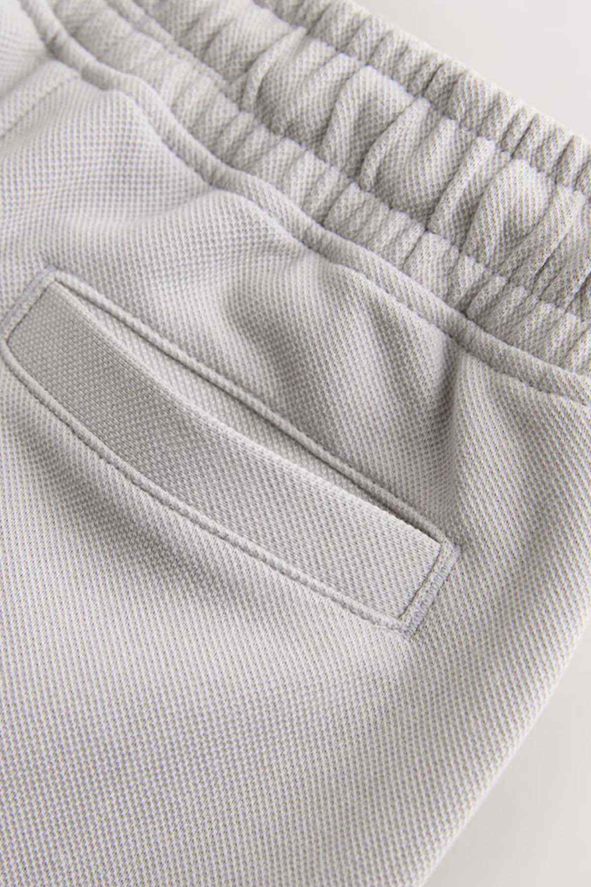 Light grey shorts front pocket and elastic waistband, textured fabric close-up