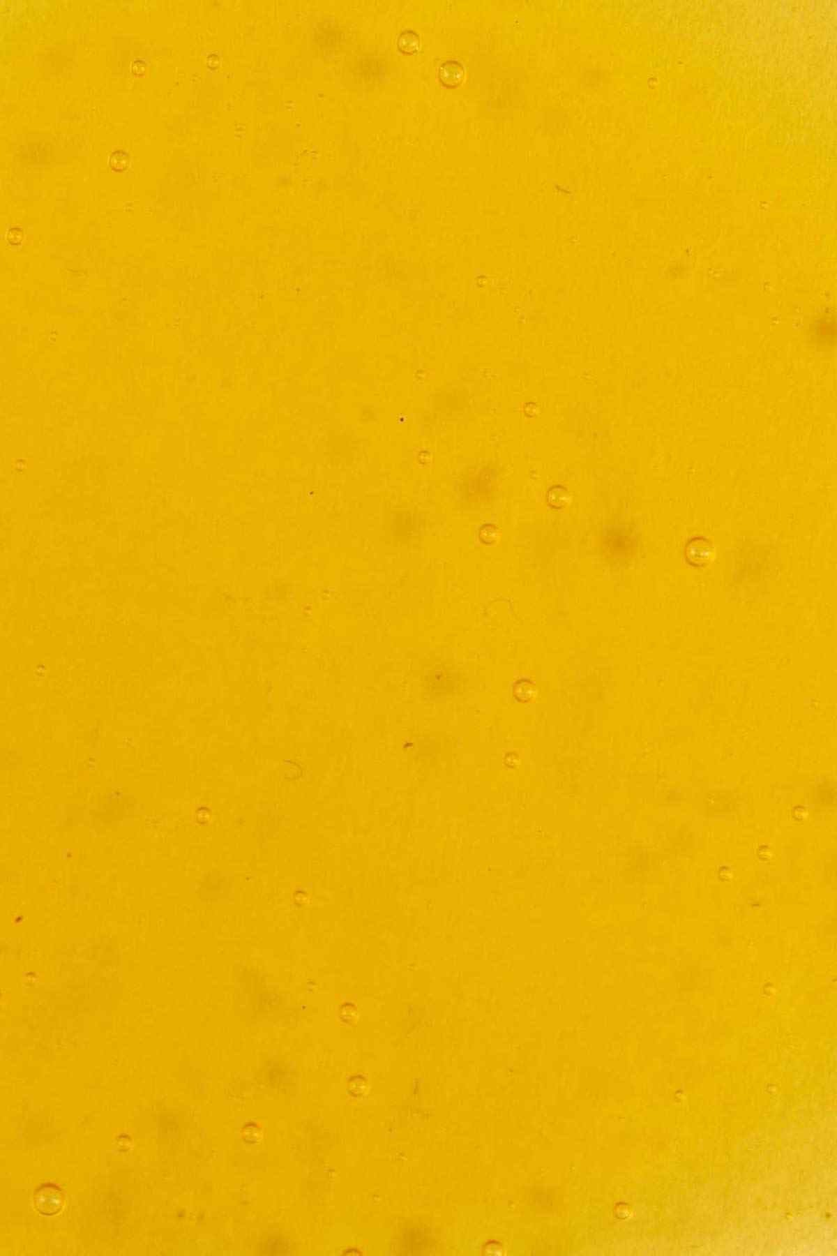 Amber skincare oil surface with small raised droplets, close-up texture