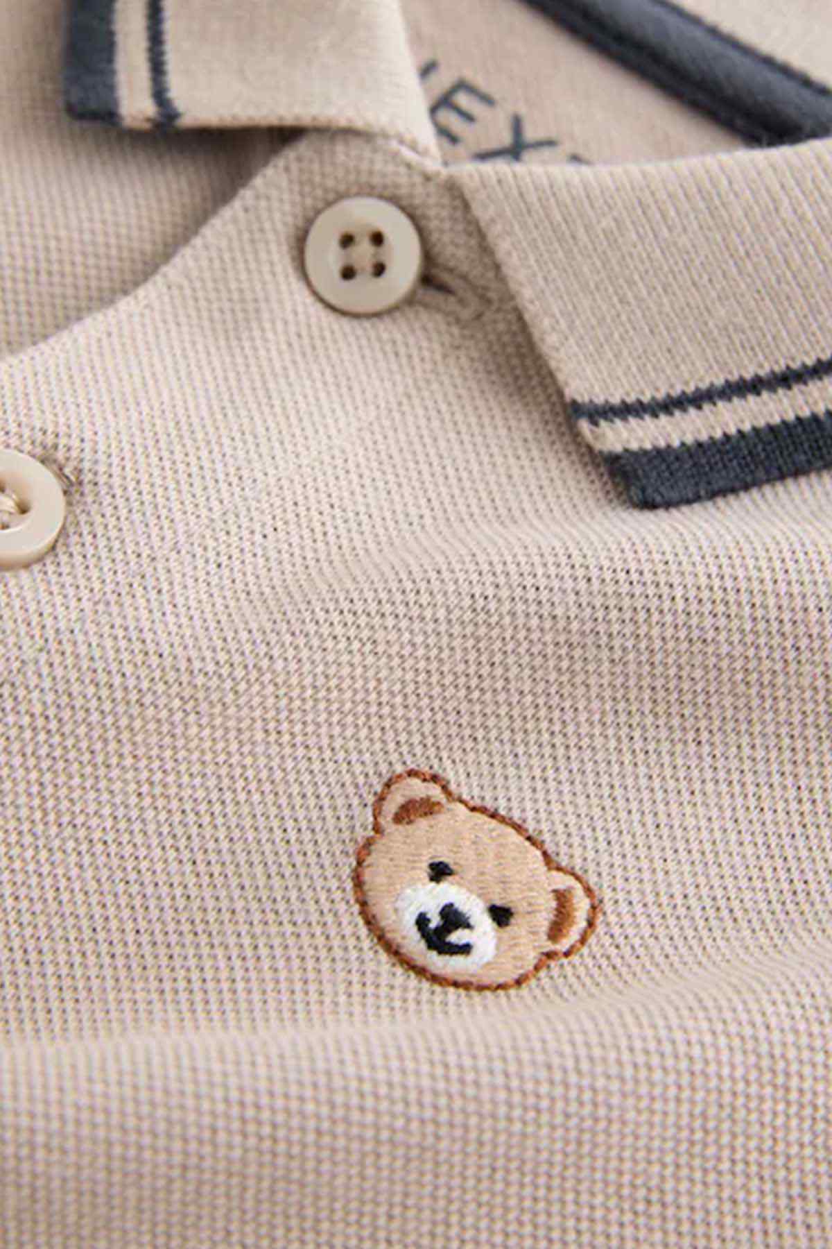 Stone polo shirt close-up: button placket and embroidered bear on chest