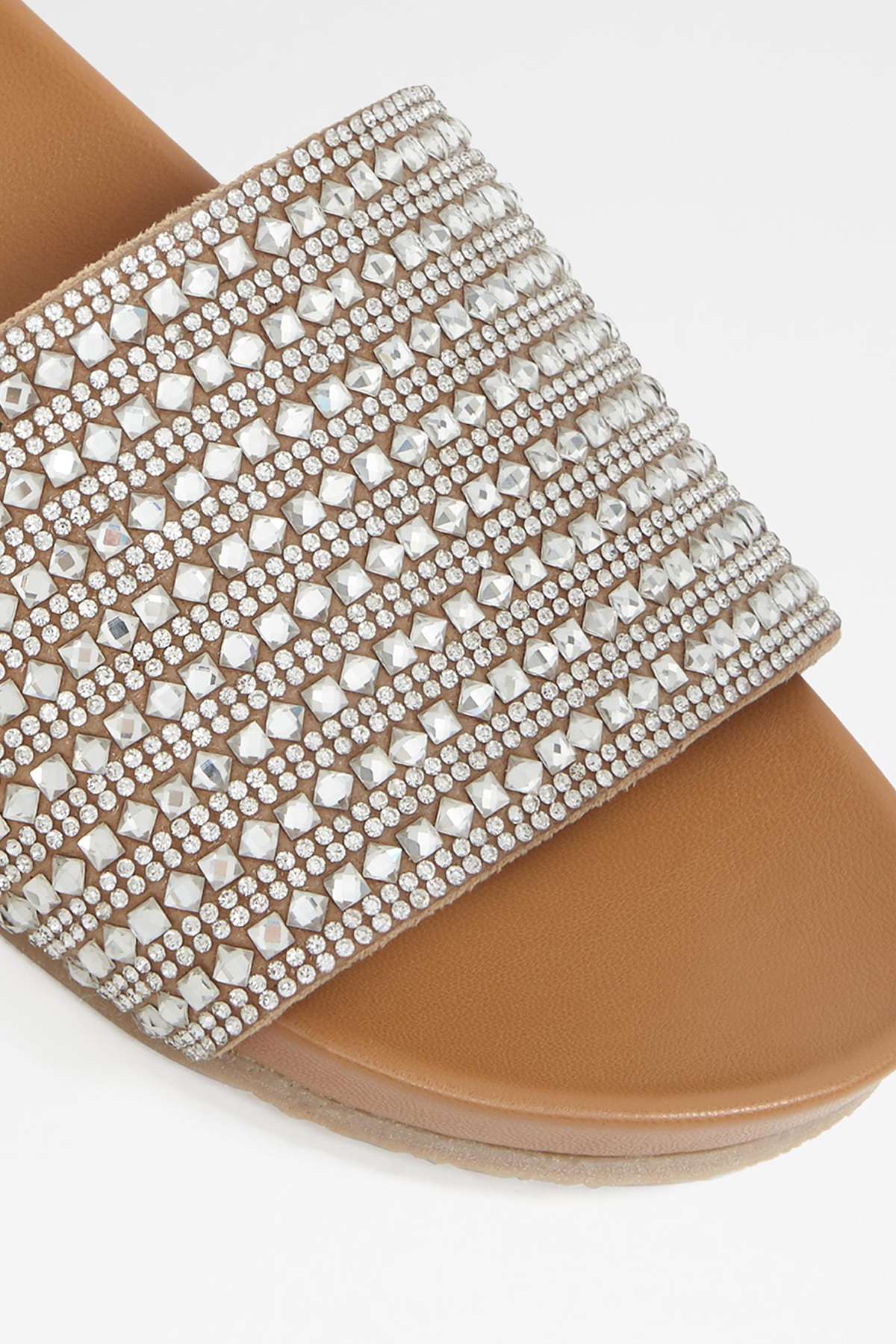 Close-up of beige rhinestone slide sandal strap over tan footbed
