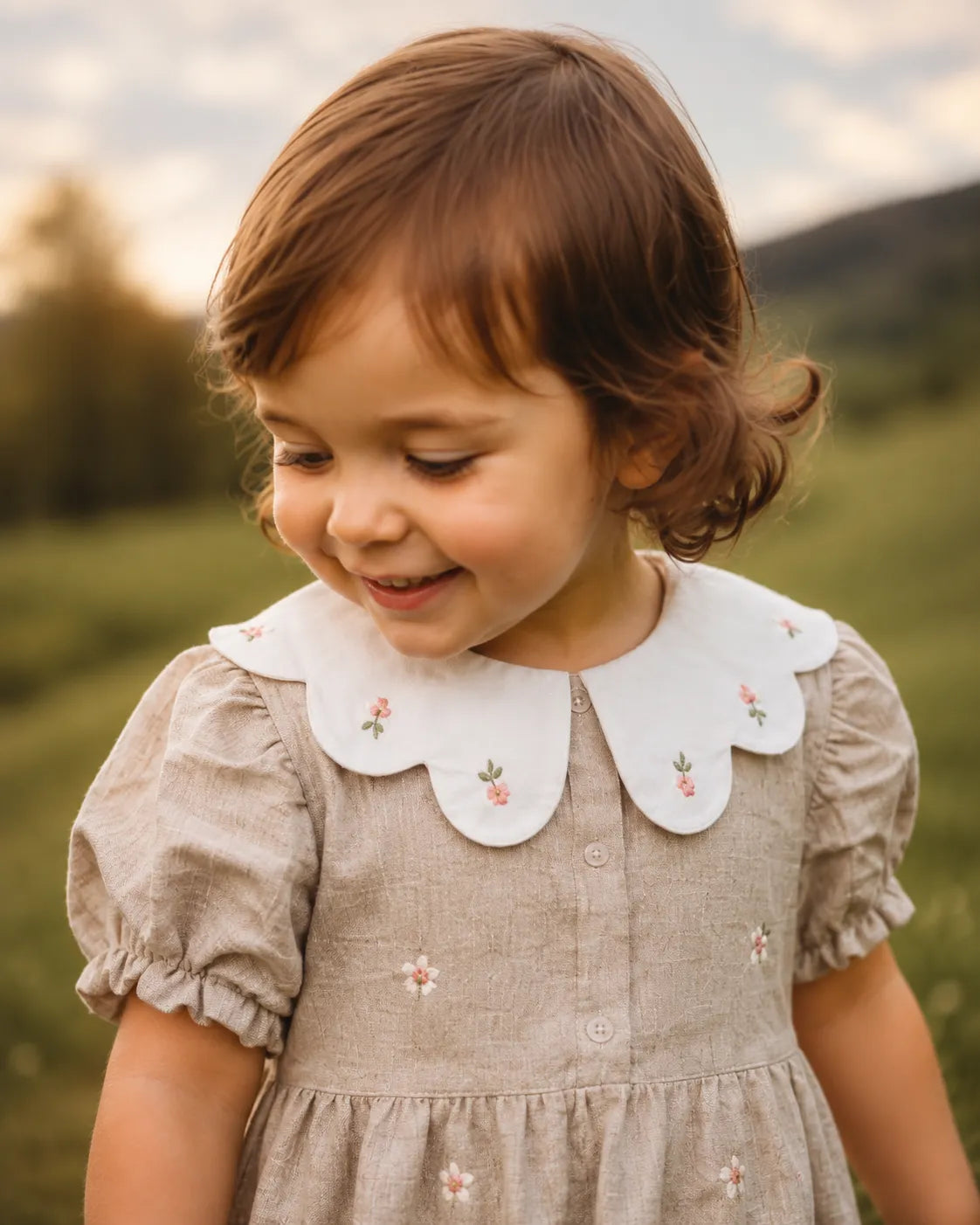 Stone baby romper with white scalloped collar and small floral embroidery, front view
