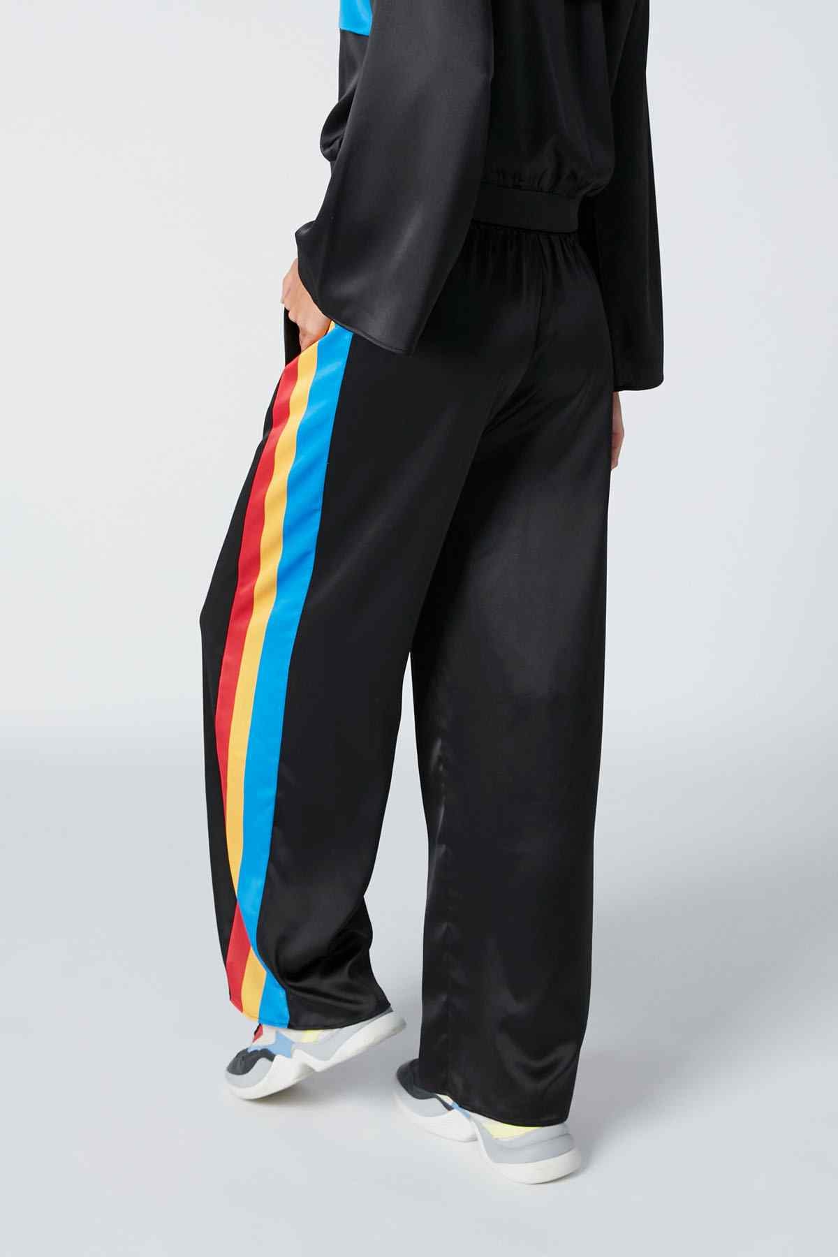 Black track pants with rainbow side stripe, elastic waist and cuffs, loose fit