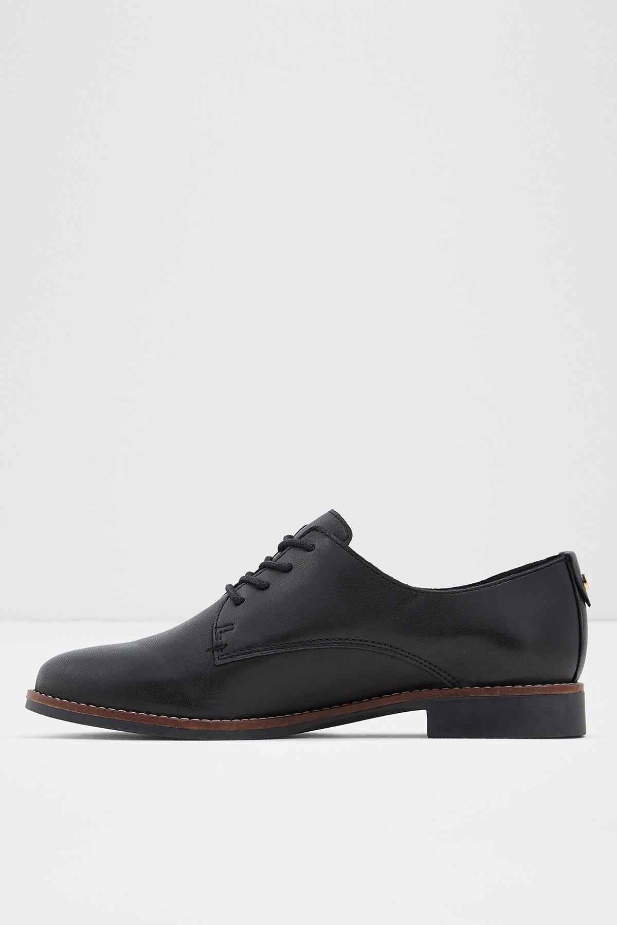 Black lace-up oxford shoe with brogue-style stitching and brown sole