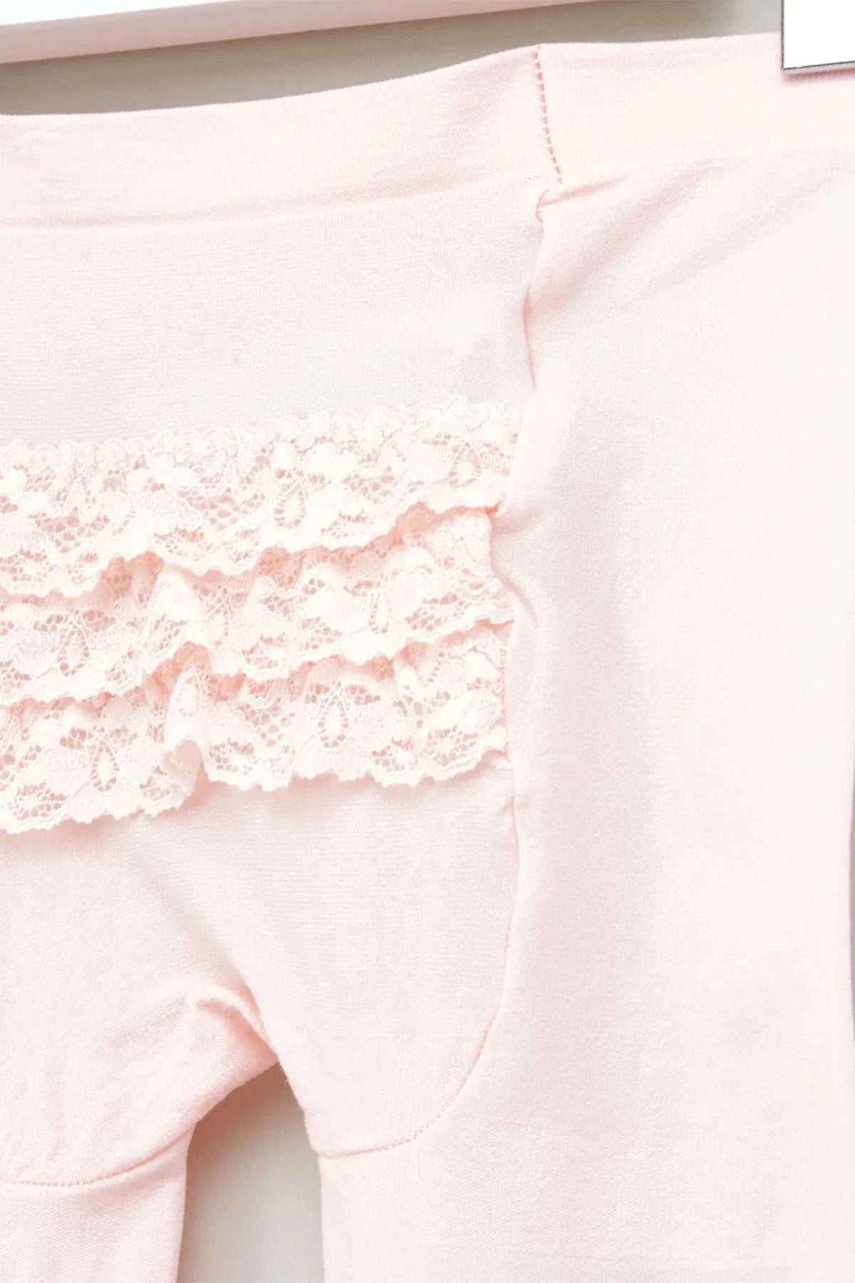 Pink baby tights close-up with lace ruffle trim at thigh