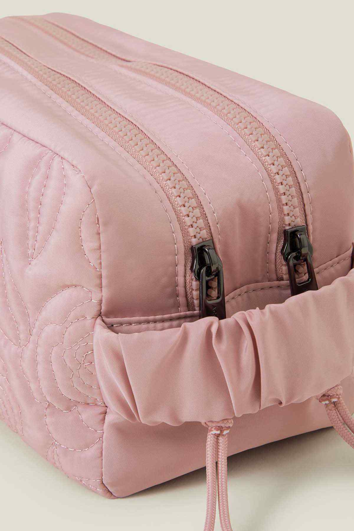 Blush quilted cosmetic bag close-up: zipper and textured quilting strap