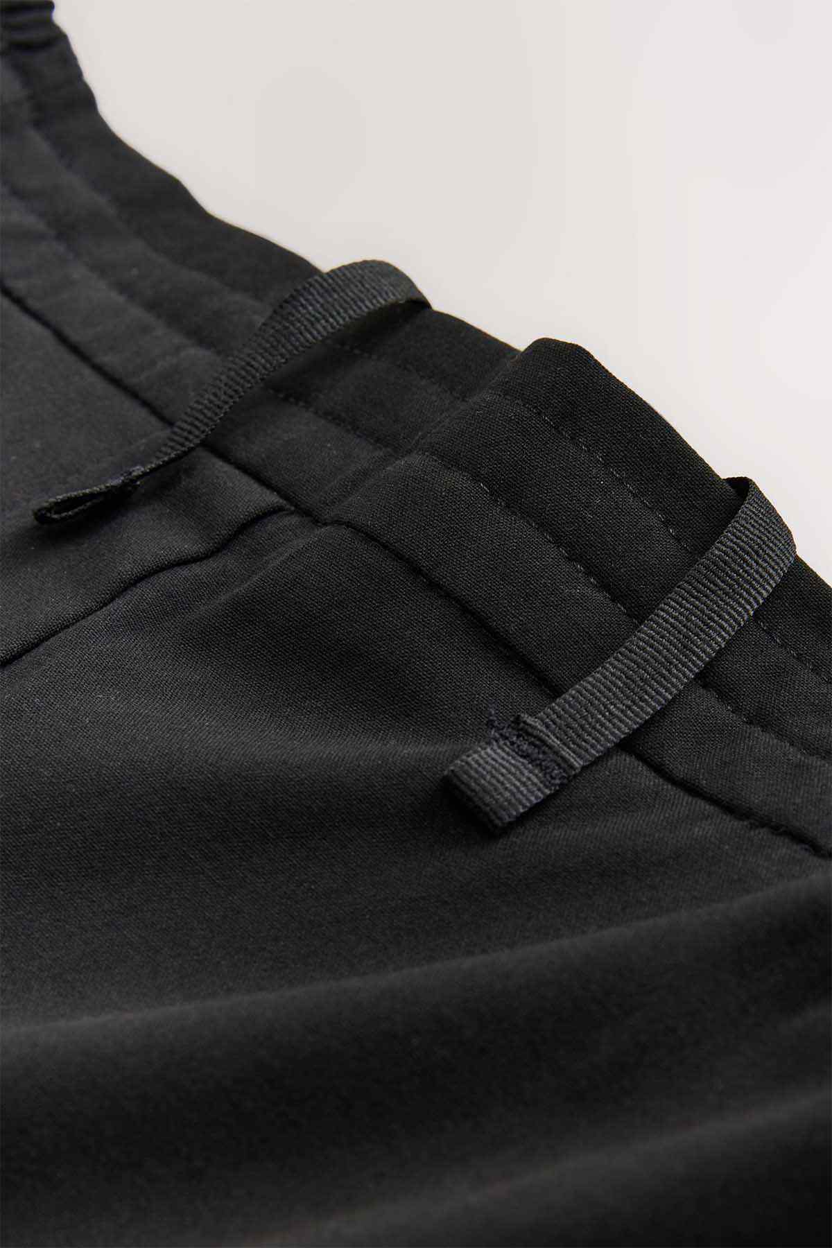 Black pants fabric detail with belt loops and stitched waistband