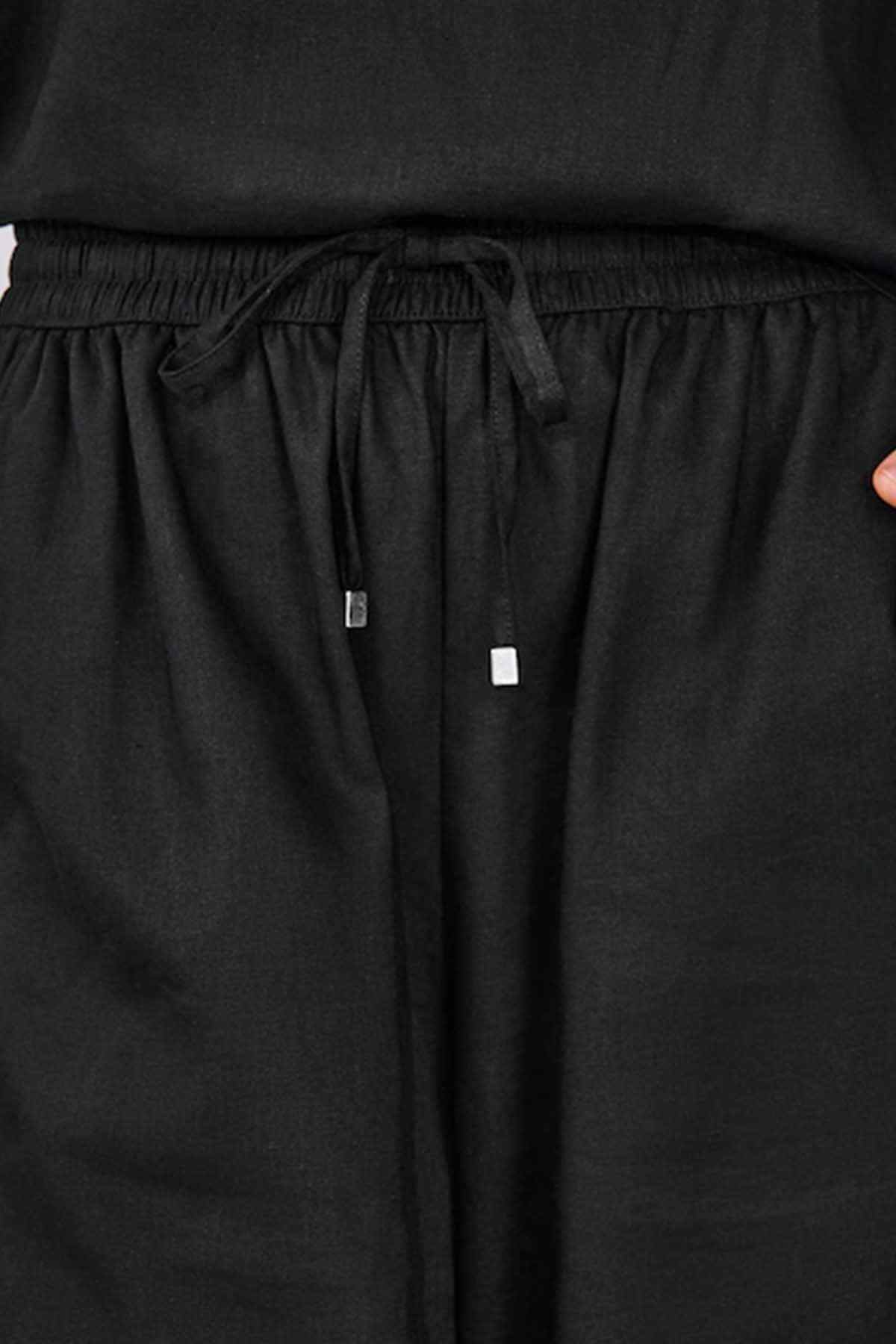 Black trousers with elastic waistband and tied drawstring with metal eyelets