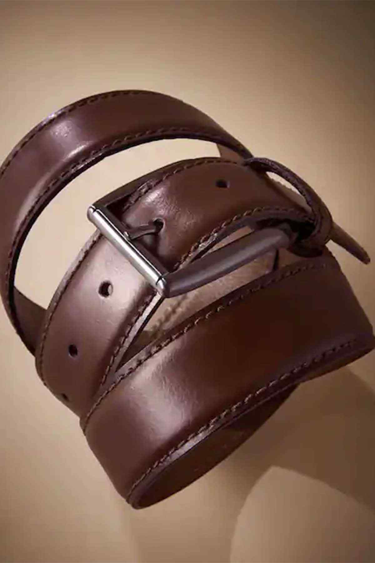Brown leather belt close-up with metal buckle and eyelets