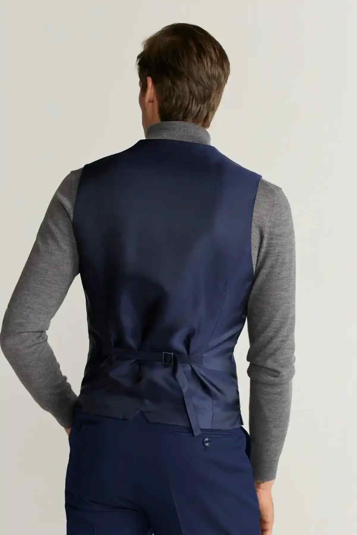 Back view of blue suit vest with adjustable waist tie, gray long sleeves
