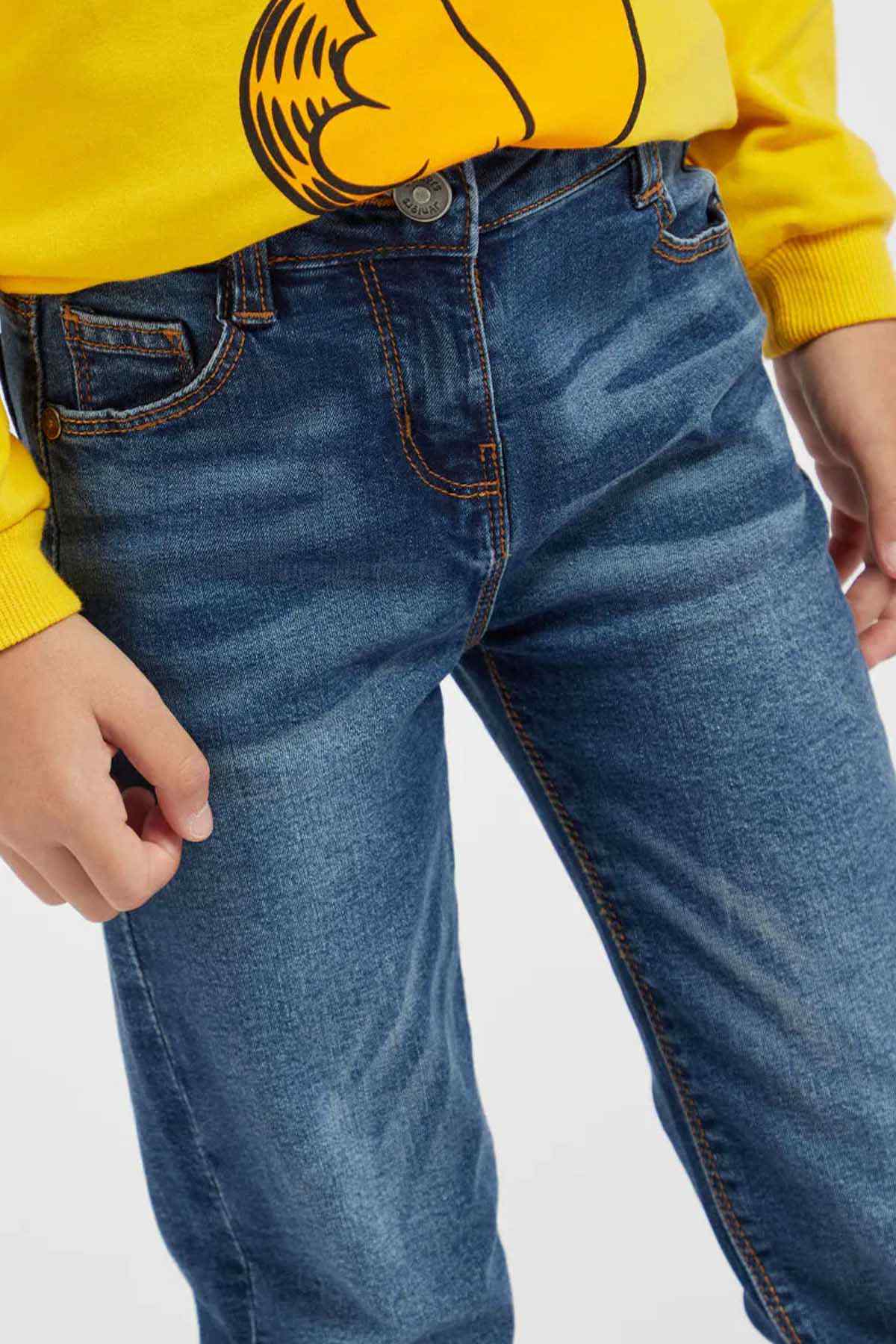 Blue denim jeans with belt loops and stitched front pocket, side view.