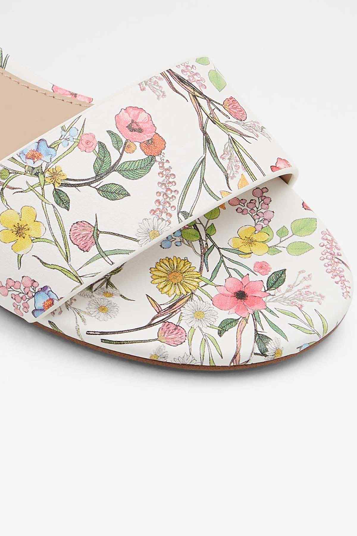 White floral flat sandal with open toe and cutout strap, close-up of printed upper