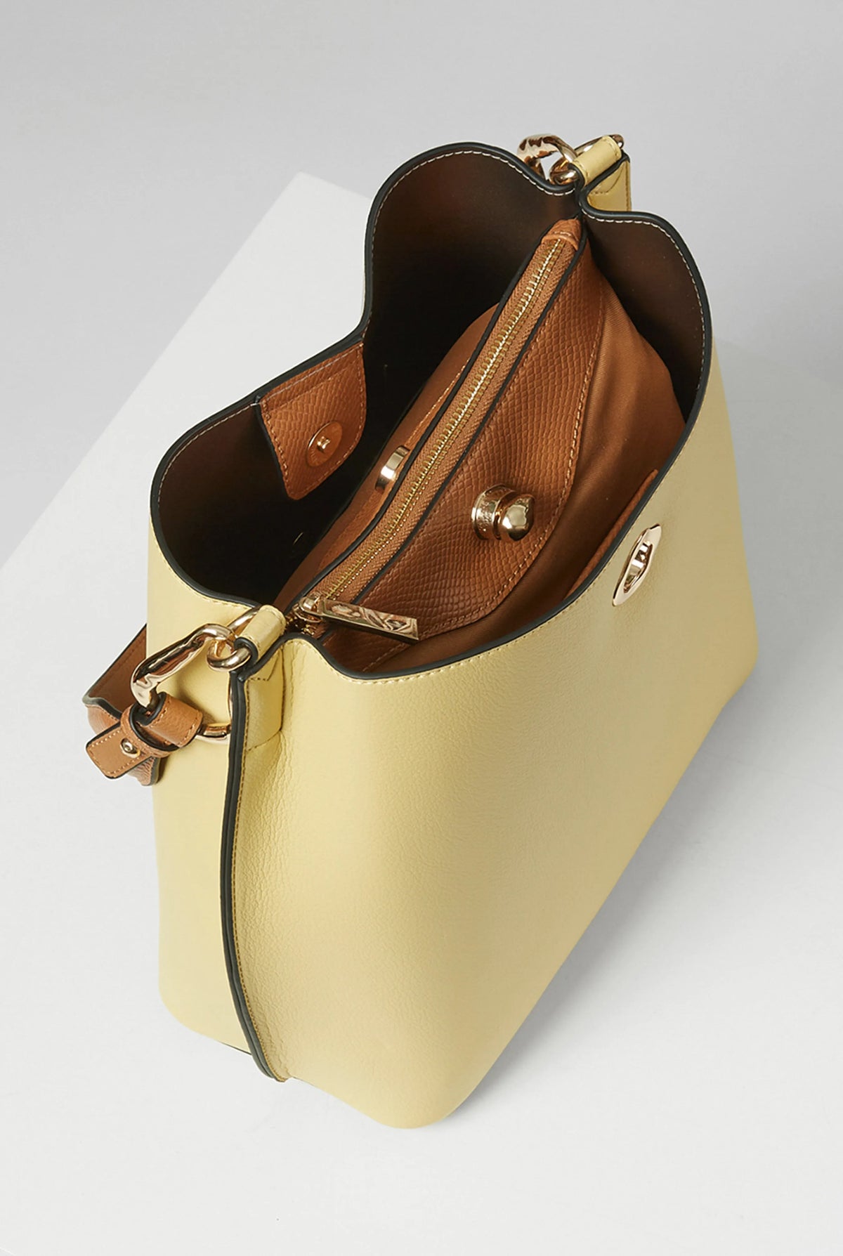 Yellow handbag open with brown lining, zip pocket, and gold hardware