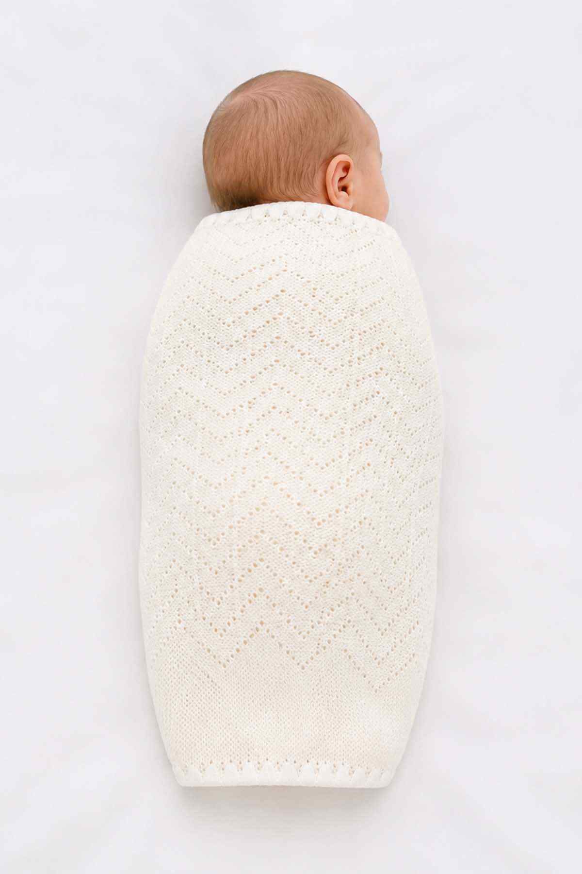 Baby shawl in white knit, back view with openwork pattern