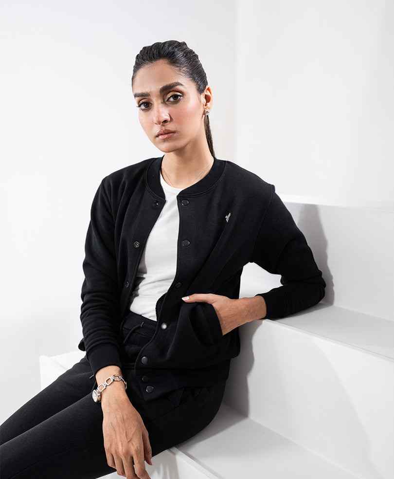 Black fitted button-front jacket with long sleeves and small chest logo, worn with dark bottoms