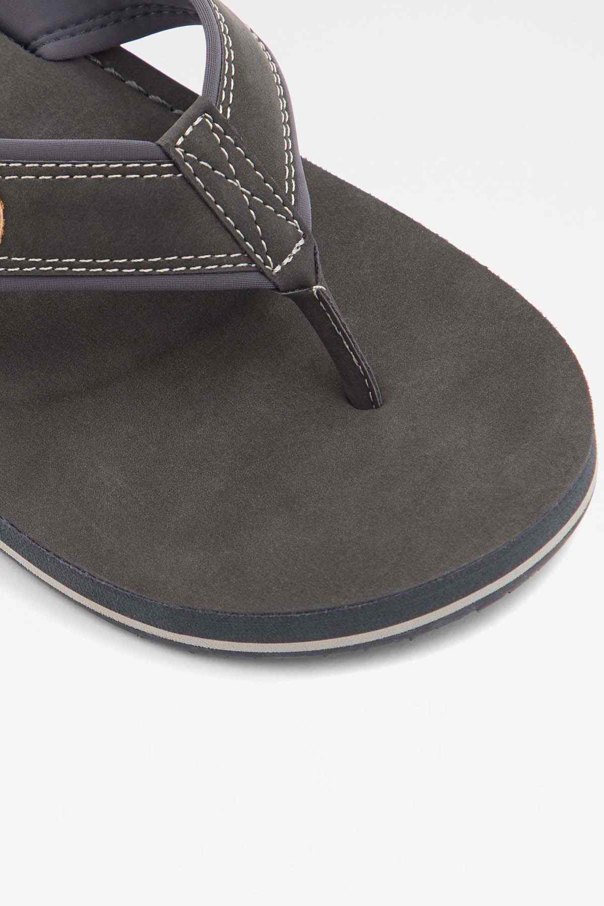 Dark gray flip-flop strap with stitched thong seam on textured sole