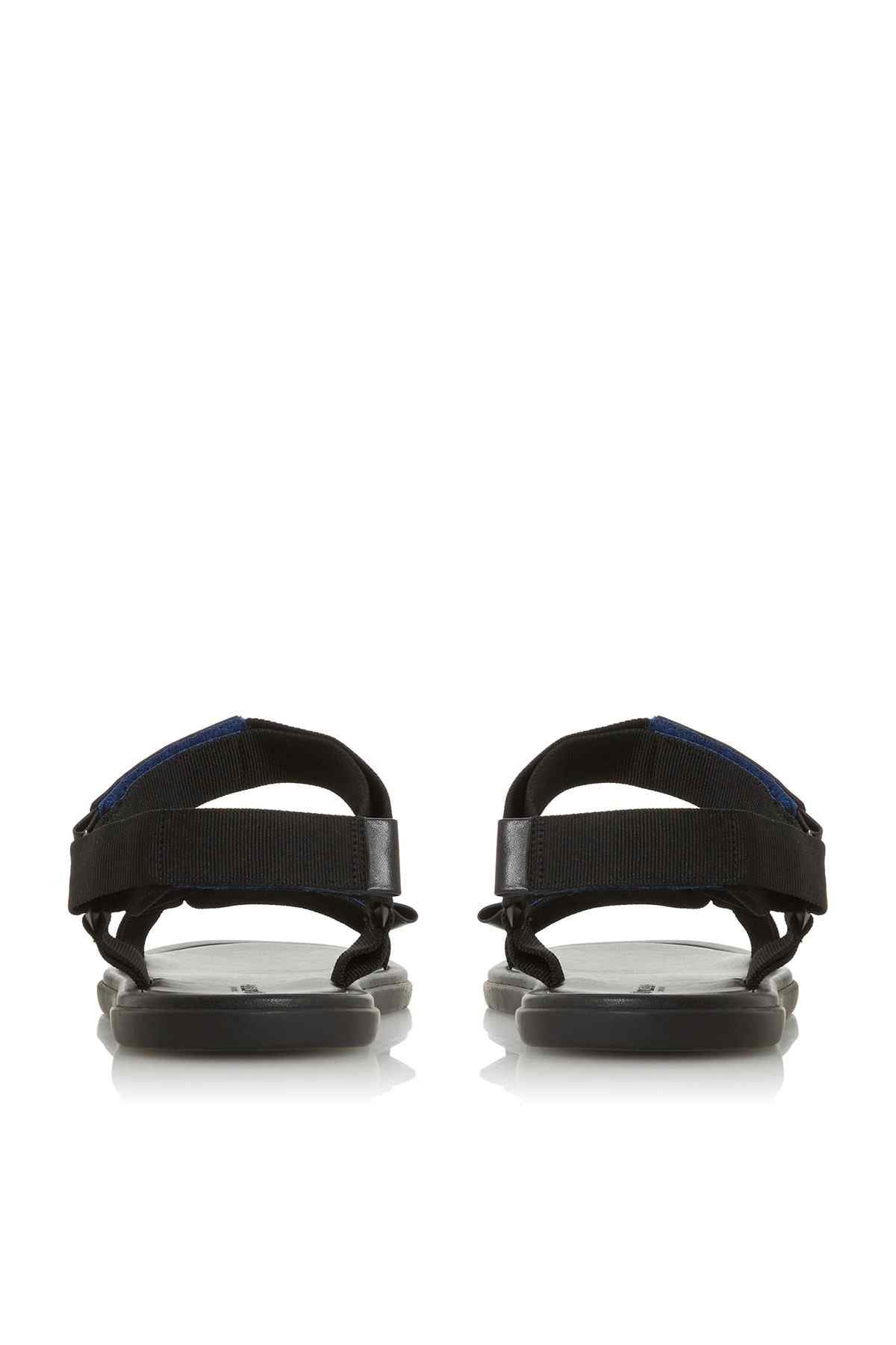 Black flat sandals with wide back straps and blue stitching detail