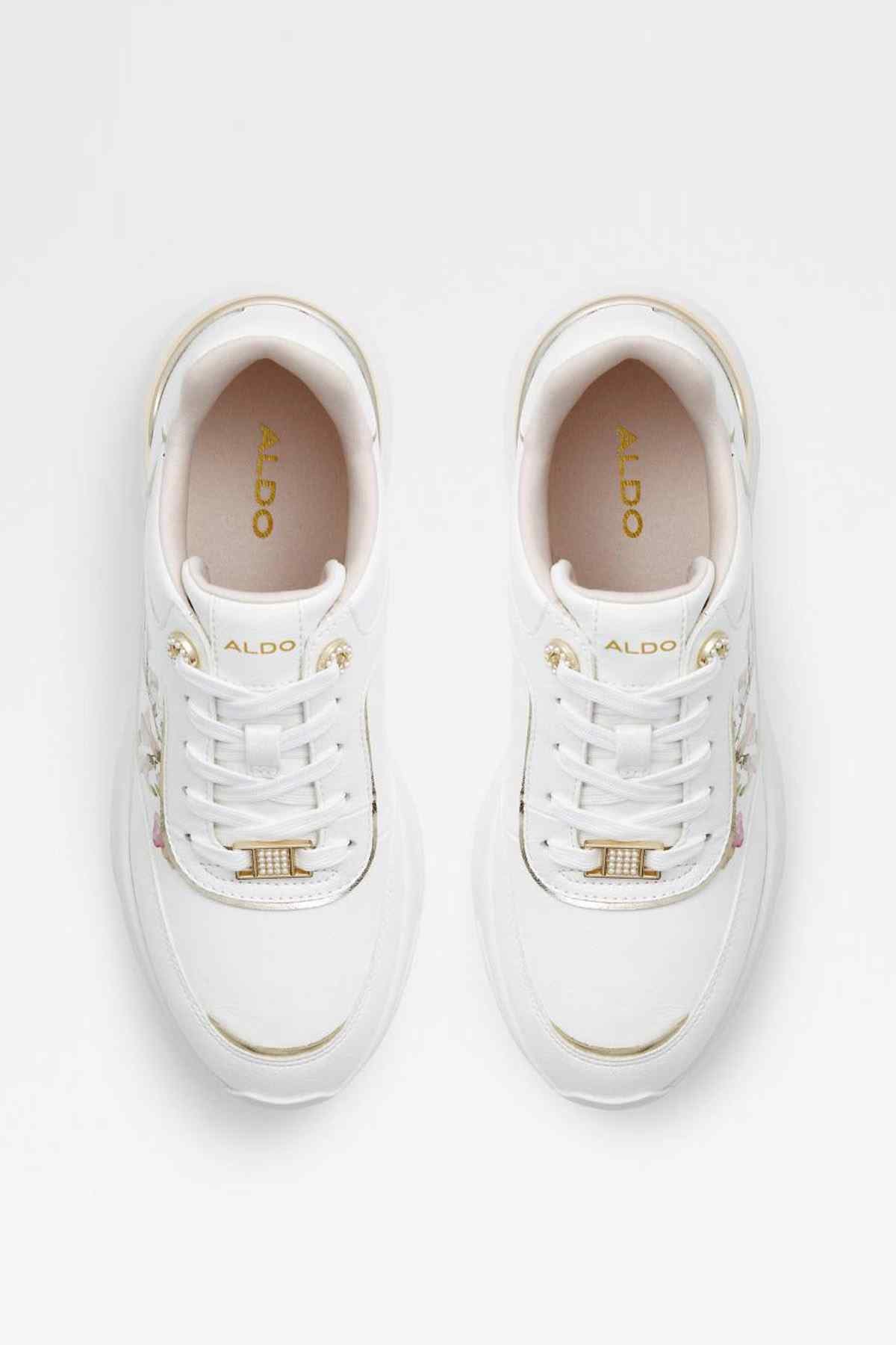 White sneakers pair with gold logo on insoles and perforated lace trim