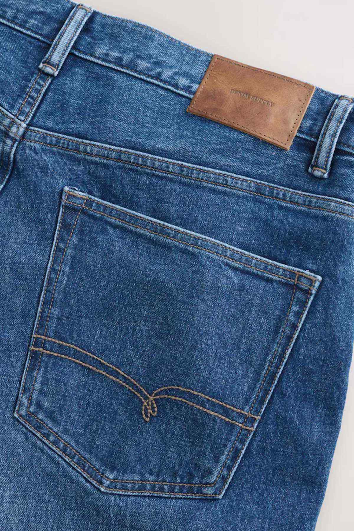 Mid blue denim jeans with stitched patch pocket and tan leather label