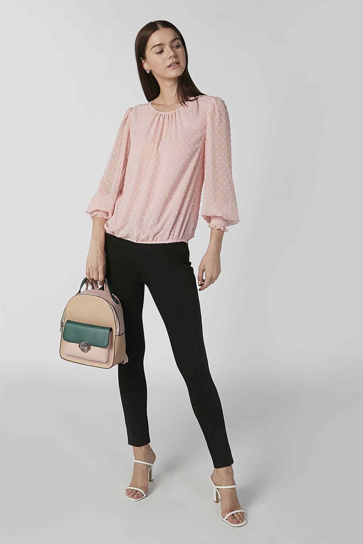 Brown backpack accessory with green flap and front clasp, worn by model