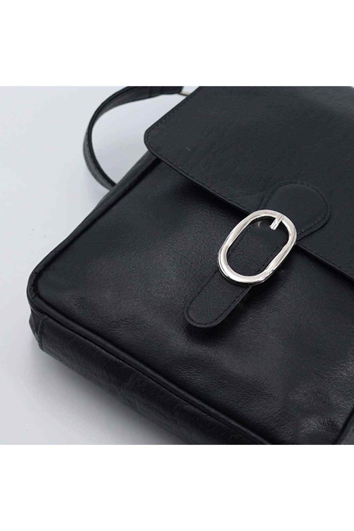 Black flap crossbody bag close-up with oval metal buckle and snap tab