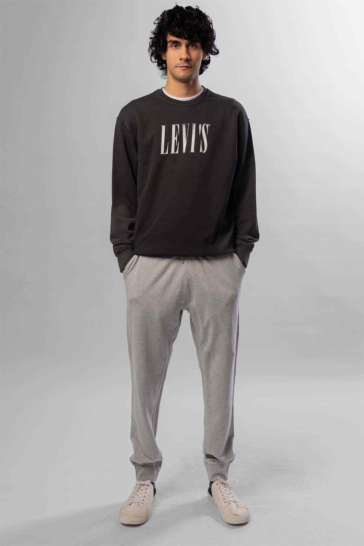 Levi's logo crewneck sweatshirt and light grey tapered joggers, standing front