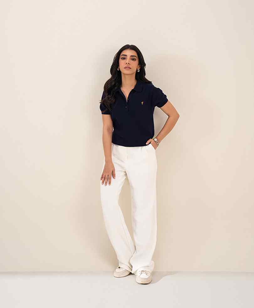 Fitted navy polo shirt with short sleeves and small chest logo, paired with white pants