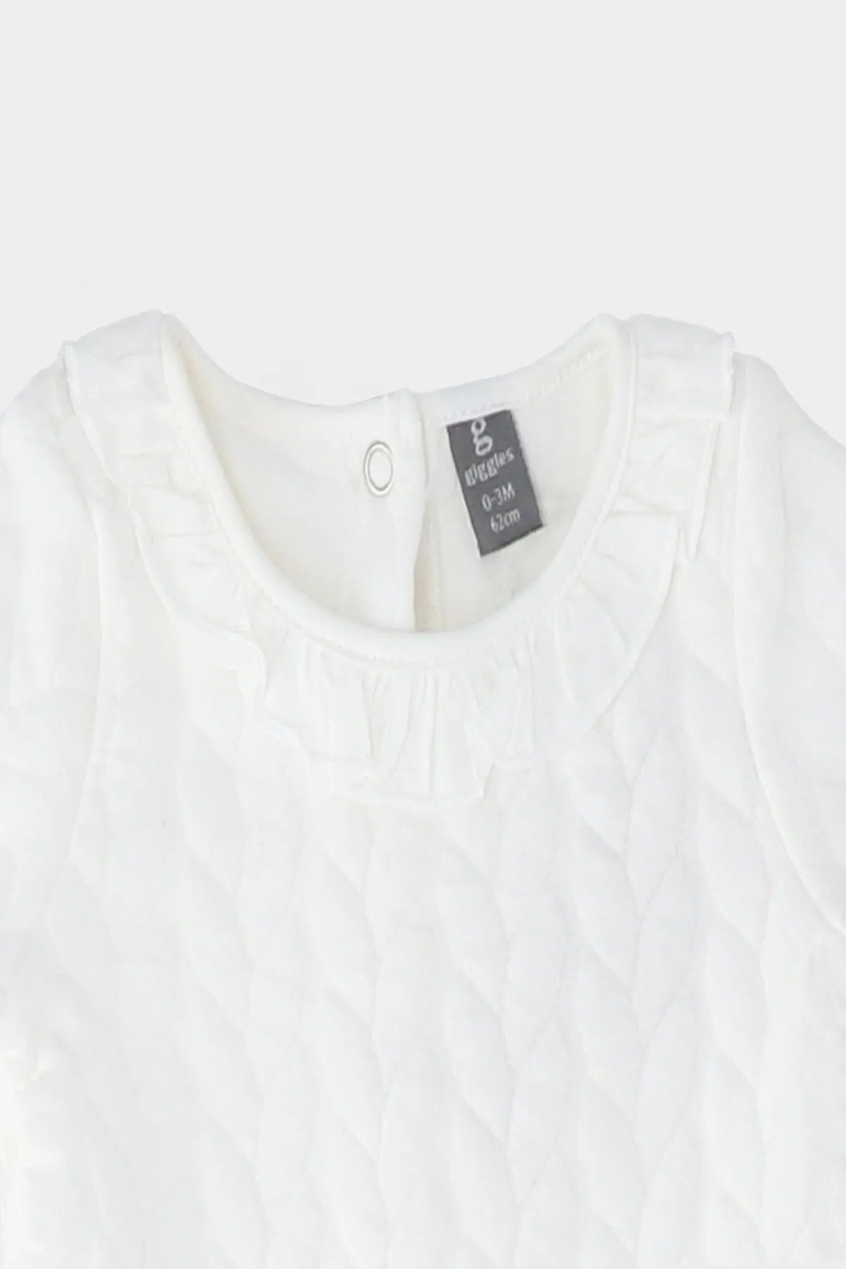 Cream baby dress neckline with small keyhole button and textured fabric