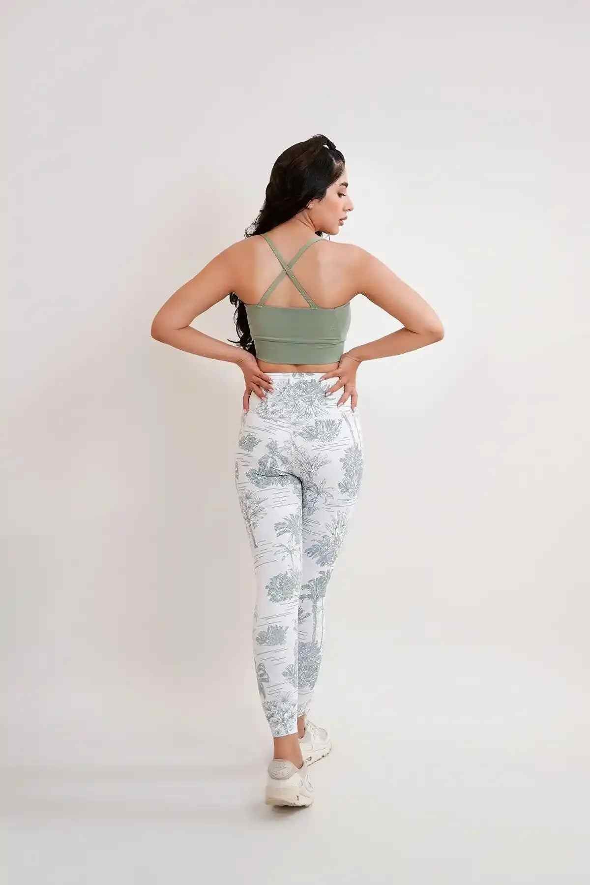 Back view of green sports bra with crisscross straps; botanical print leggings