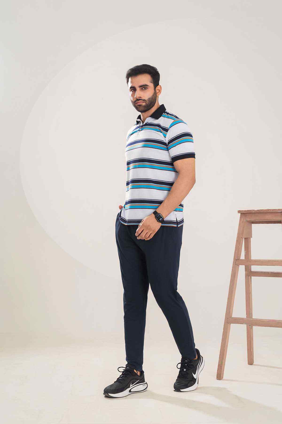 Men's striped polo shirt with collar and navy pants, three-quarter stance